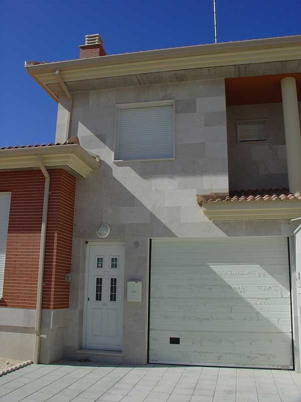 Fachada de una de las viviendas con los acabados de puerta de entrada y puerta de garaje de16 viviendas unifamiliares Íscar
